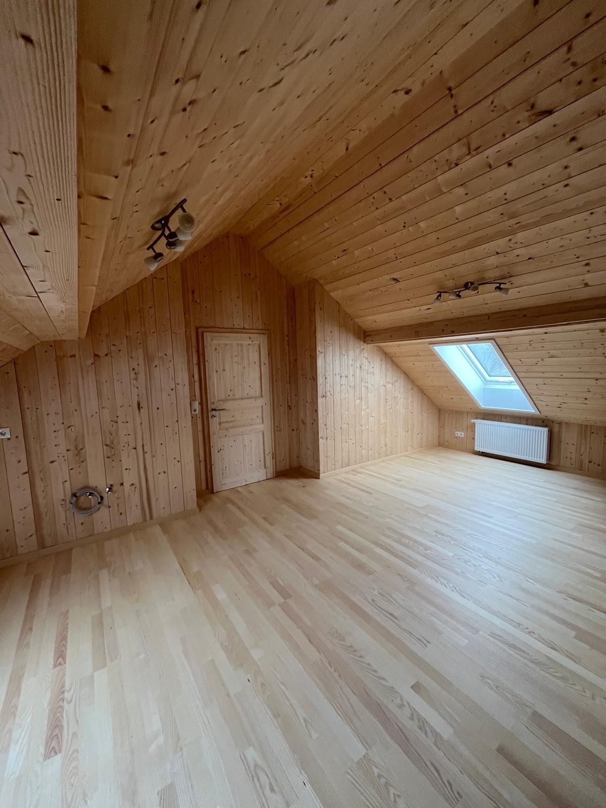 Gemütliche, geschlossene Veranda mit Holzwänden, hängenden Weblampen und hellen Möbeln.