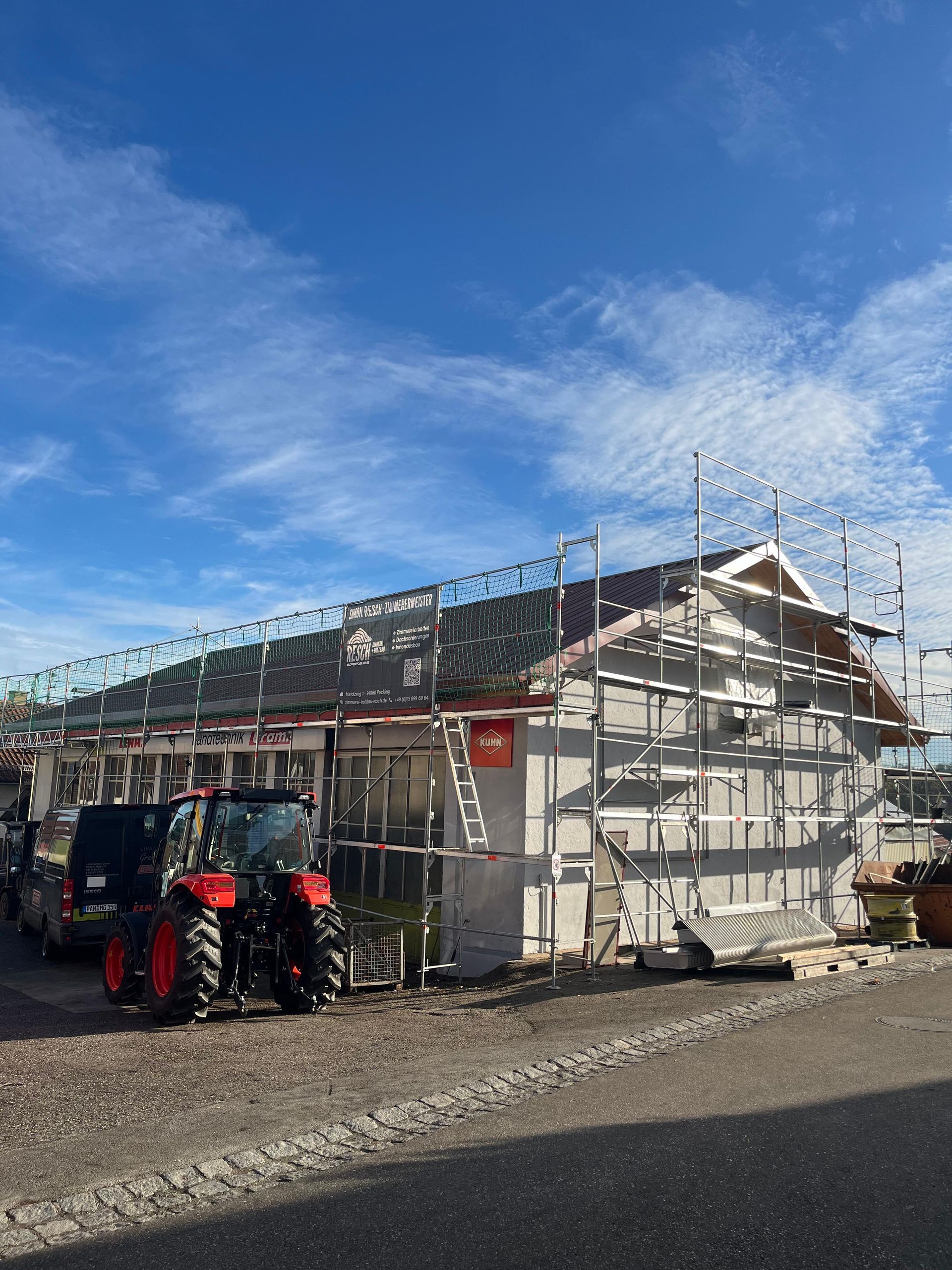Gebäude im Bau, Gerüst, Dacharbeiten, grüne Sicherheitsnetze, klarer Himmel.