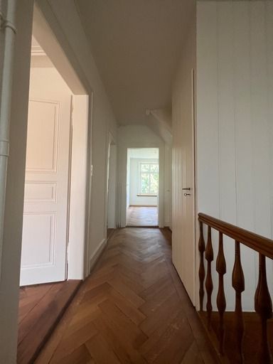 Ein Flur mit Holzboden und weißen Wänden