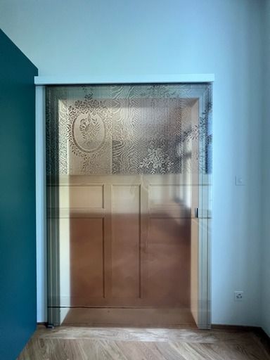 Ein Raum mit Glasschiebetür und Holzboden.