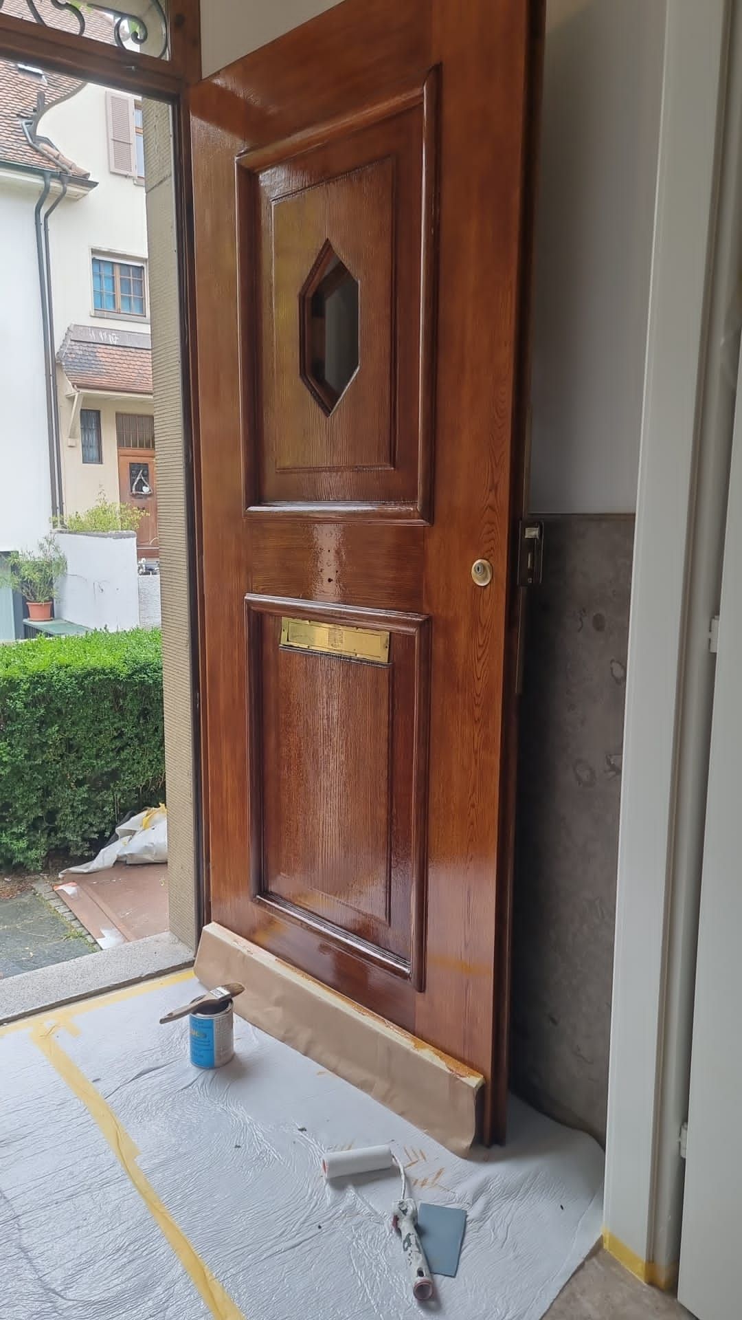 In einem Zimmer wird eine Holztür gestrichen.