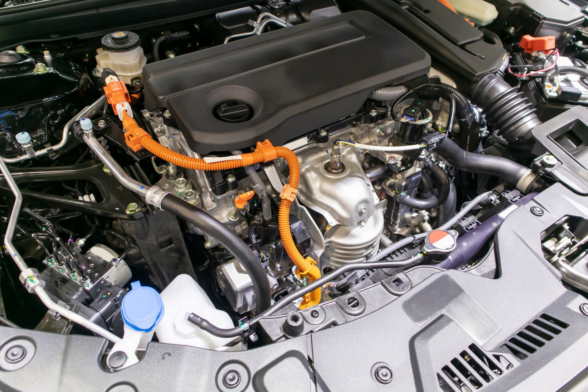 Compartiment moteur avec câblage haute tension orange et réservoirs de fluides visibles