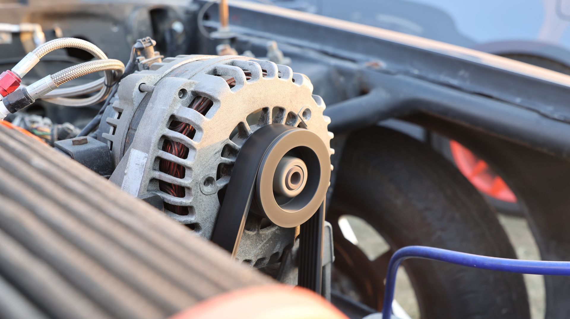 Gros plan sur un alternateur de moteur de voiture avec ses courroies et son câblage sous le capot