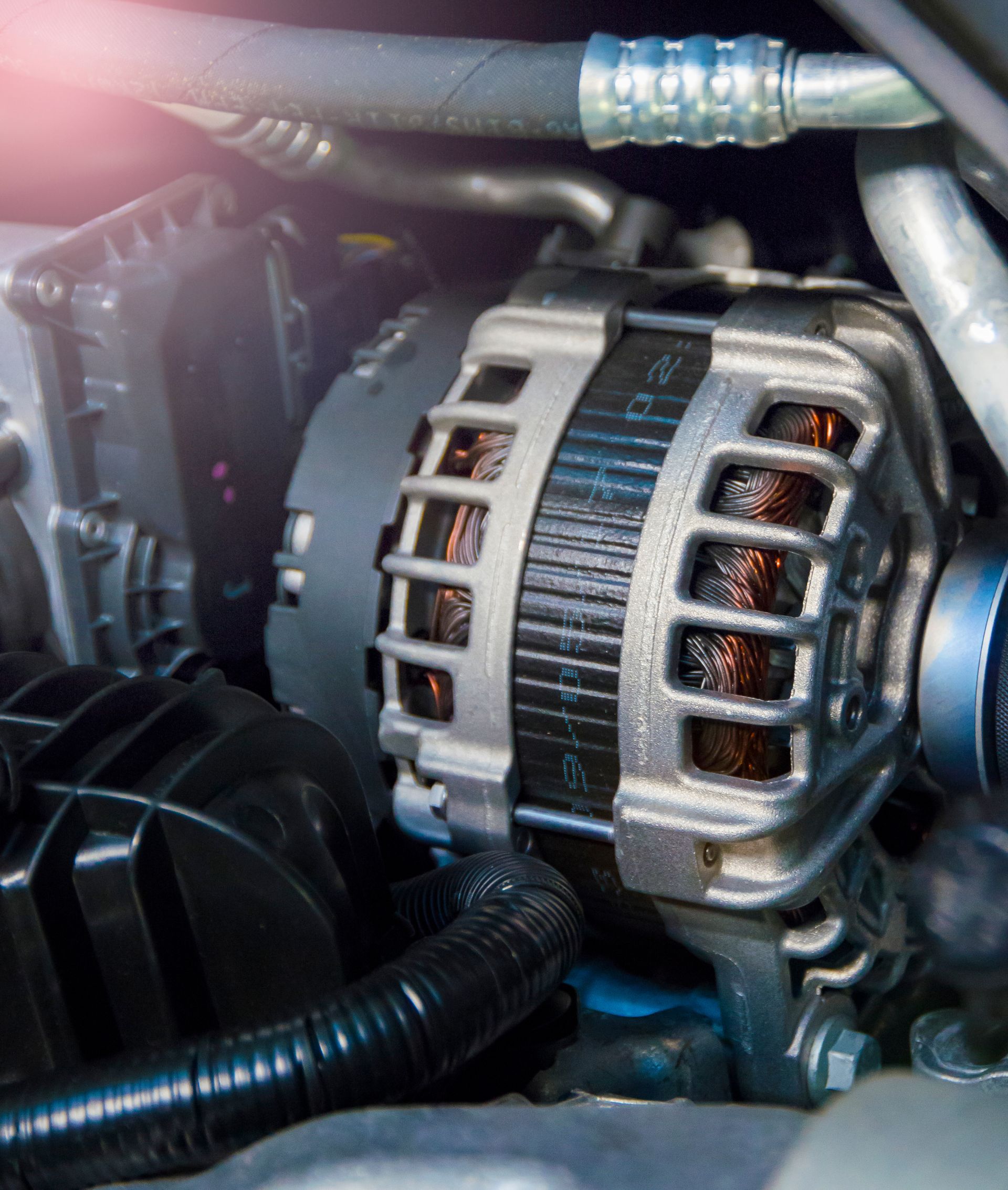 Gros plan sur un alternateur de voiture avec boîtier métallique et enroulements en cuivre dans le compartiment moteur