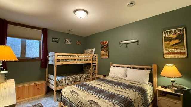 Bedroom with bunk beds, double bed, green walls, fishing-themed decor, and wooden furniture.