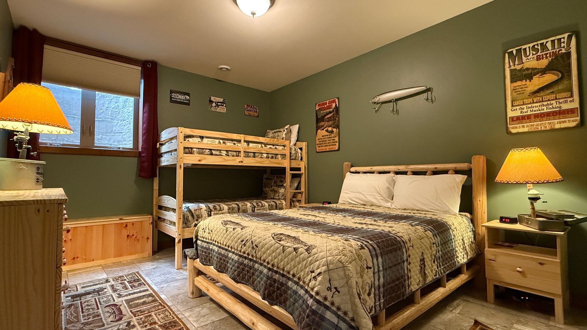 Bedroom with bunk beds, double bed, and rustic decor. Green walls, wooden furniture, and warm lighting.