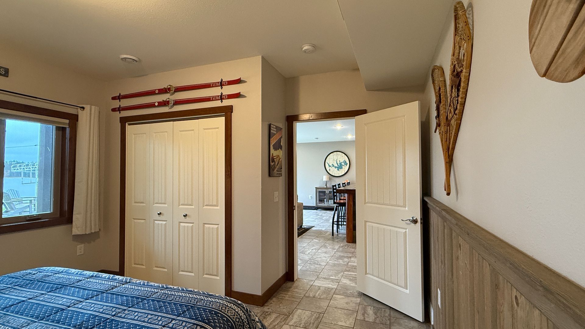 Bedroom with closet, doorway to dining area, bed with blue blanket, wood accents.