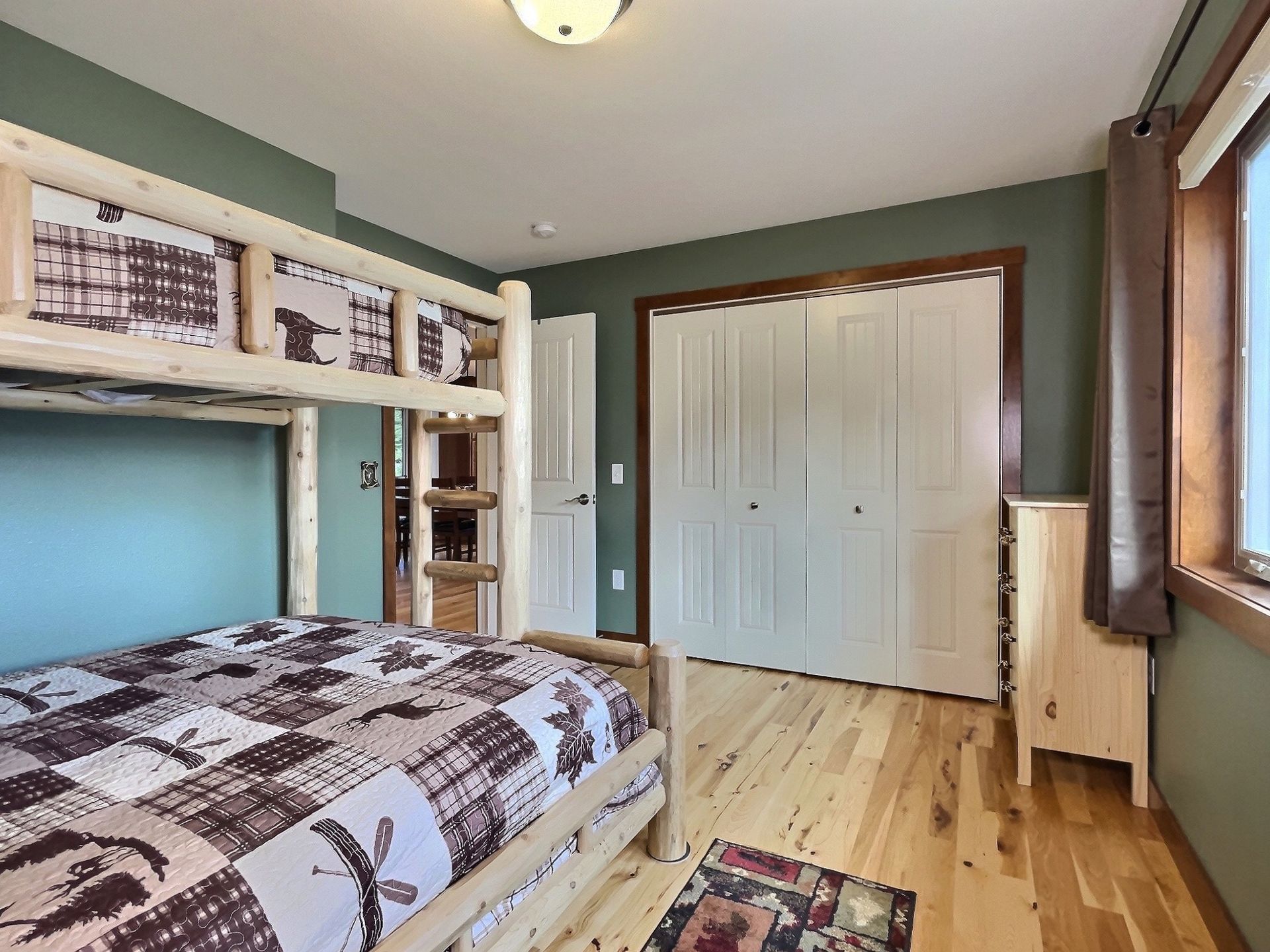 Bunk bed in a bedroom with wood floors, green walls, and a closet.