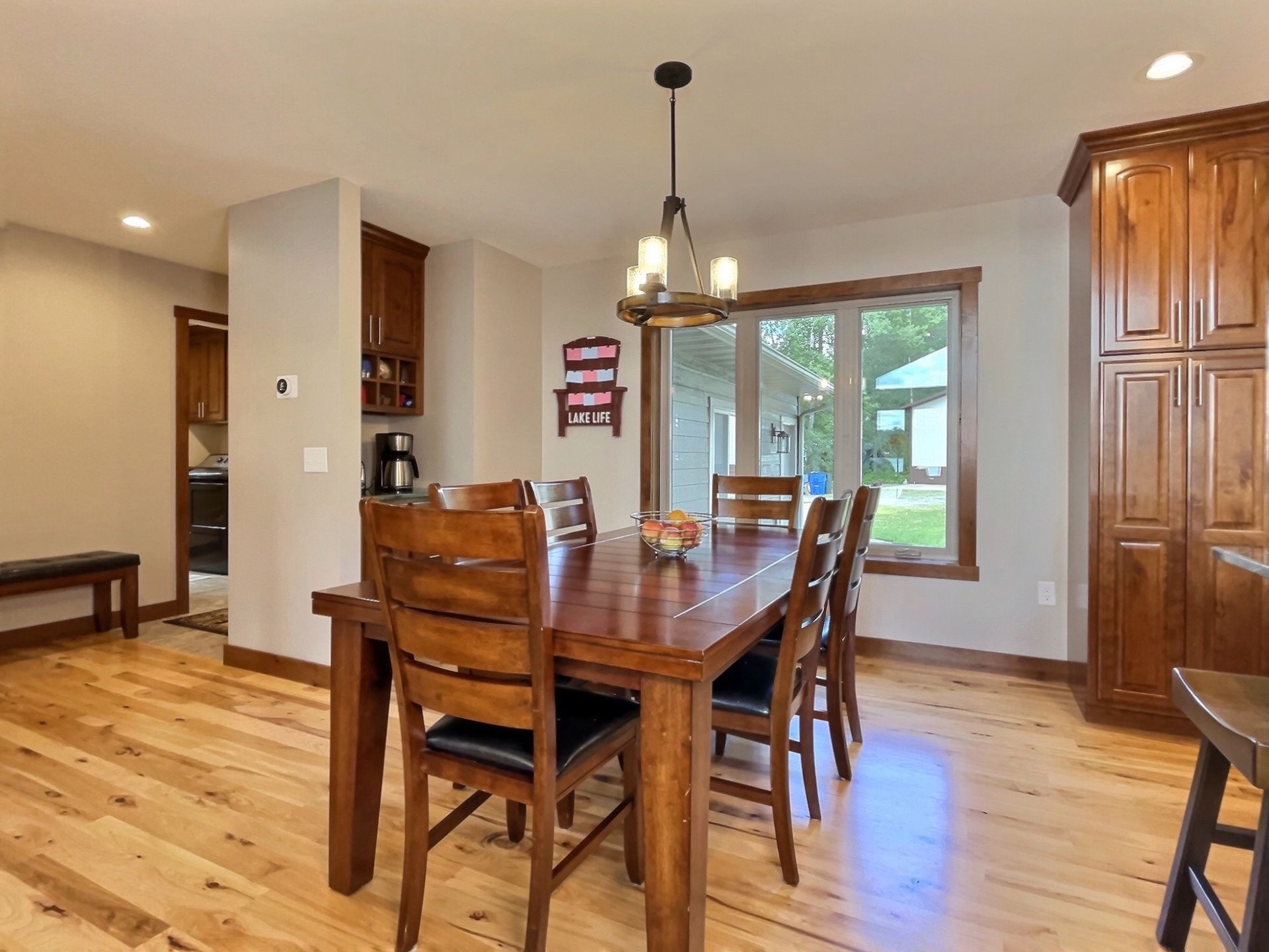 Dining room with wooden table and chairs, hardwood floor, natural light from a window.