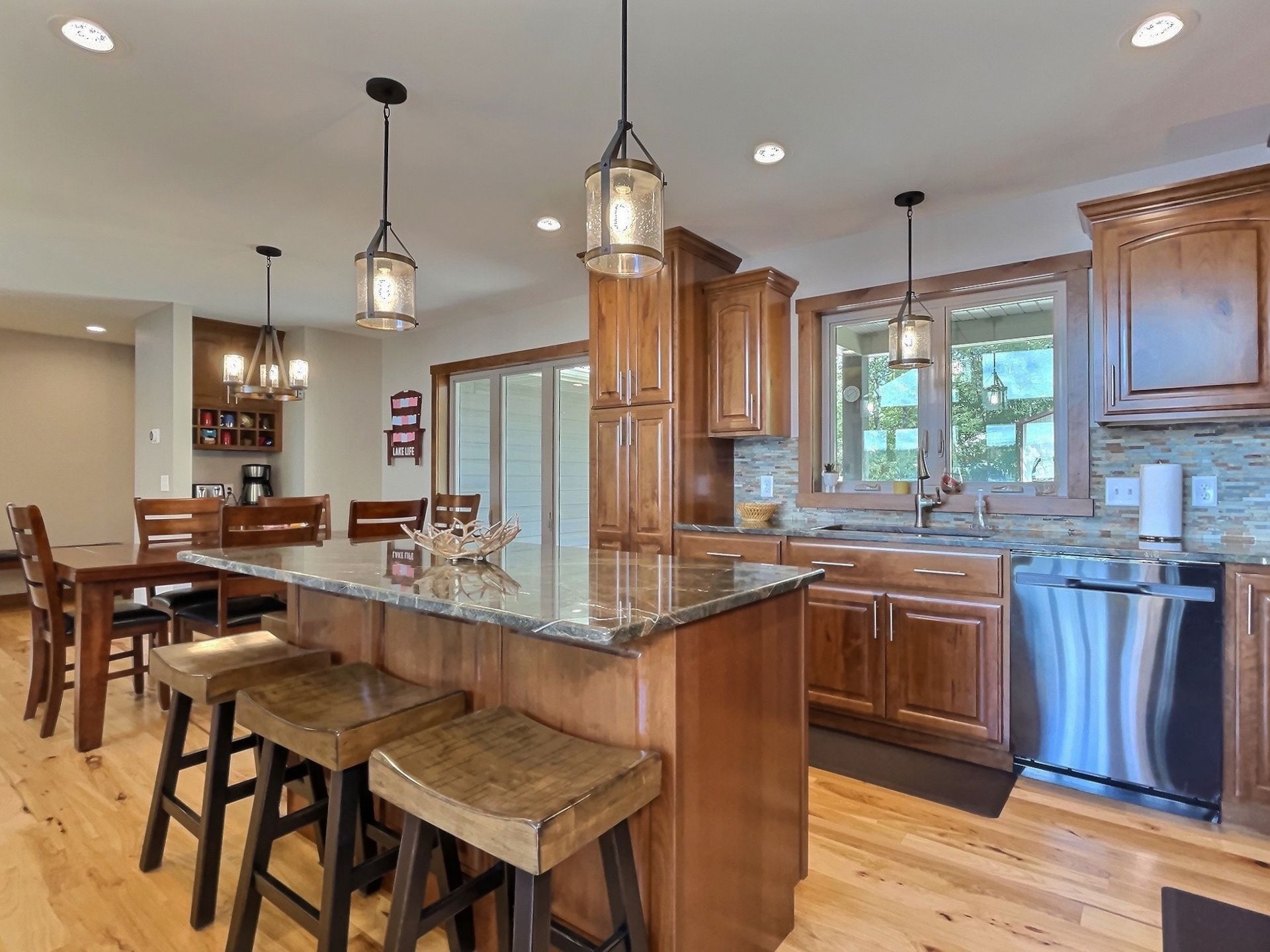 Kitchen with wooden cabinets, island with stools, granite countertop, and stainless steel appliances.