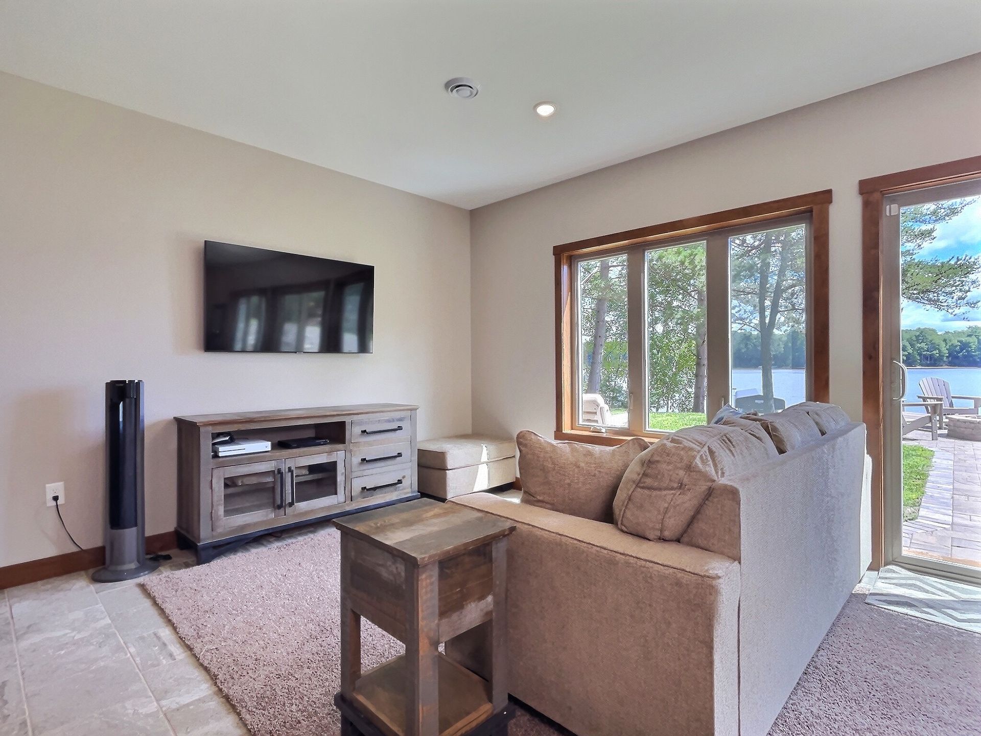 Living room with a sofa, TV, and view of a lake through large windows.