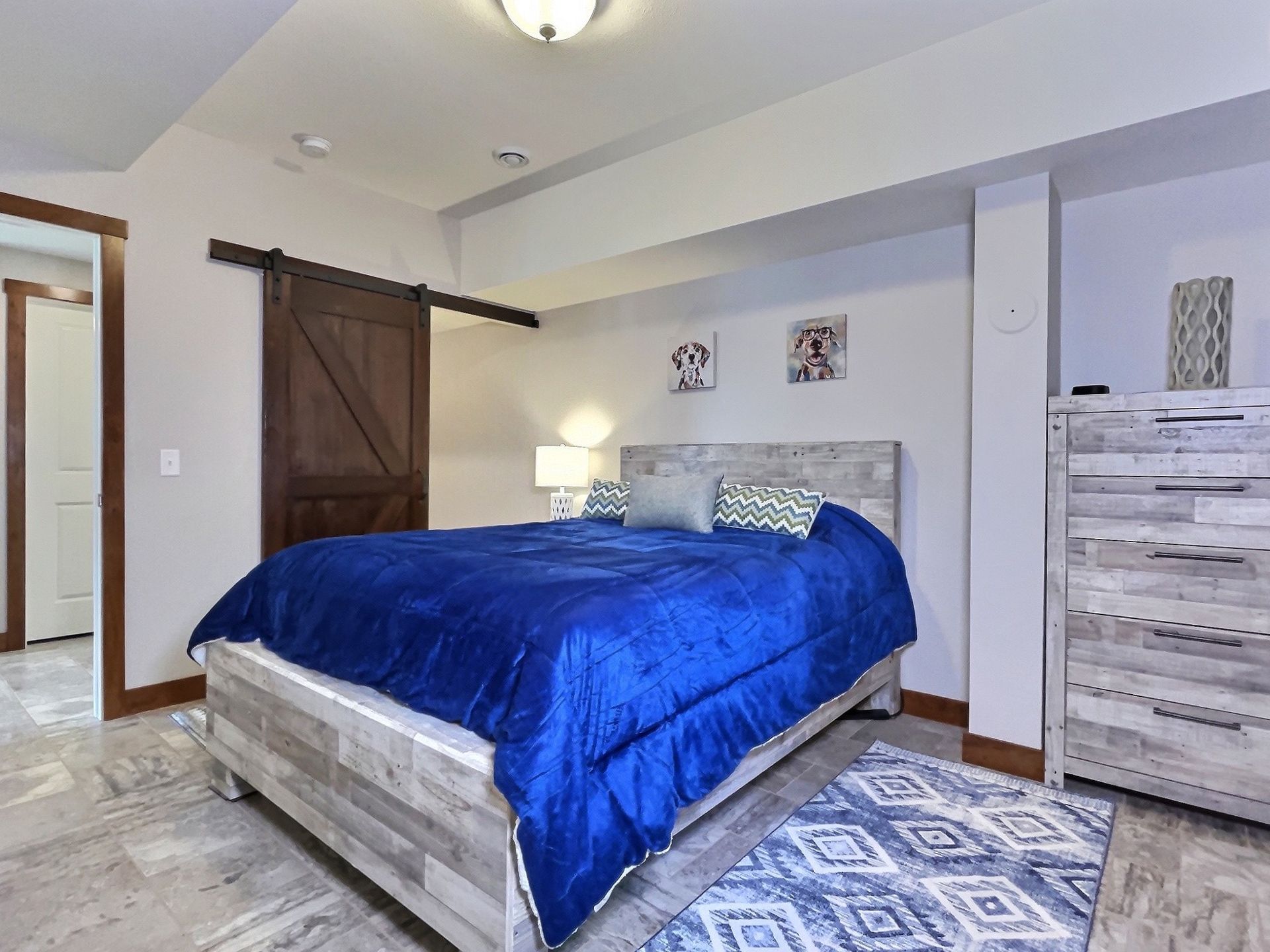 Bedroom with blue bedding, rustic wooden headboard, and sliding barn door.