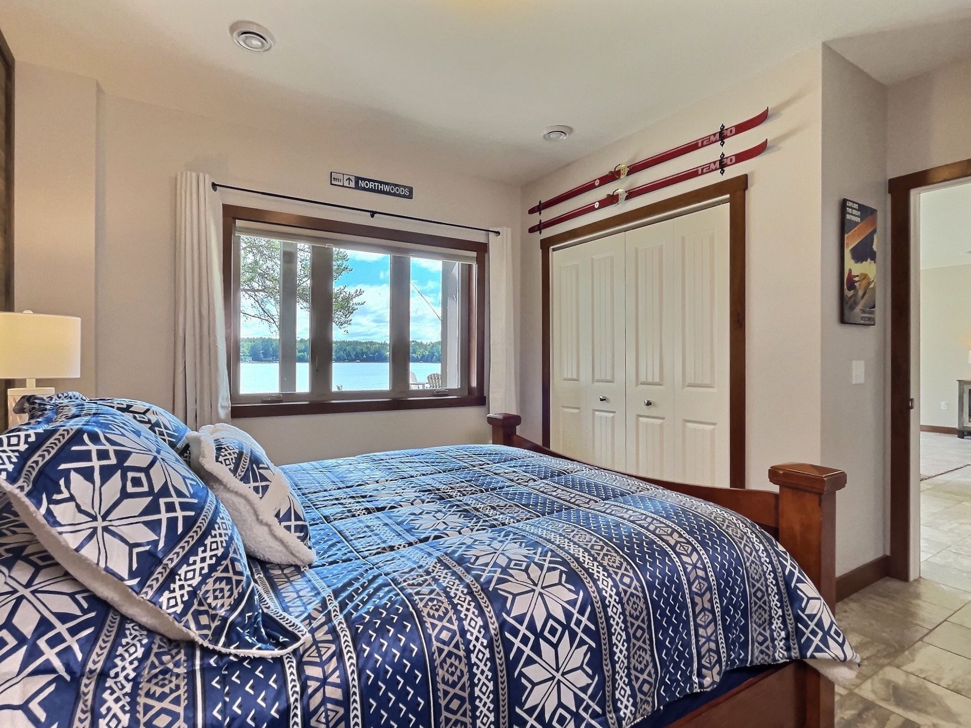 Cozy bedroom with a bed, lake view, and ski decor. Blue and white patterned bedding.