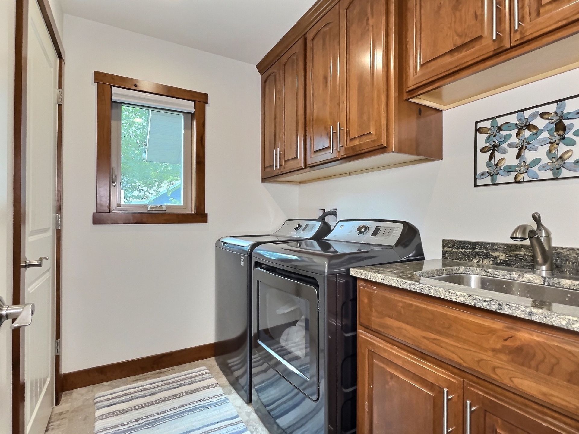 Laundry room with washer, dryer, cabinets, and a sink.