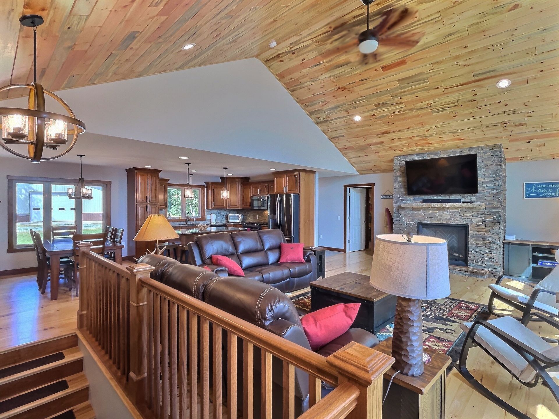 Living room with a wooden ceiling, leather sofa, fireplace, and open kitchen.