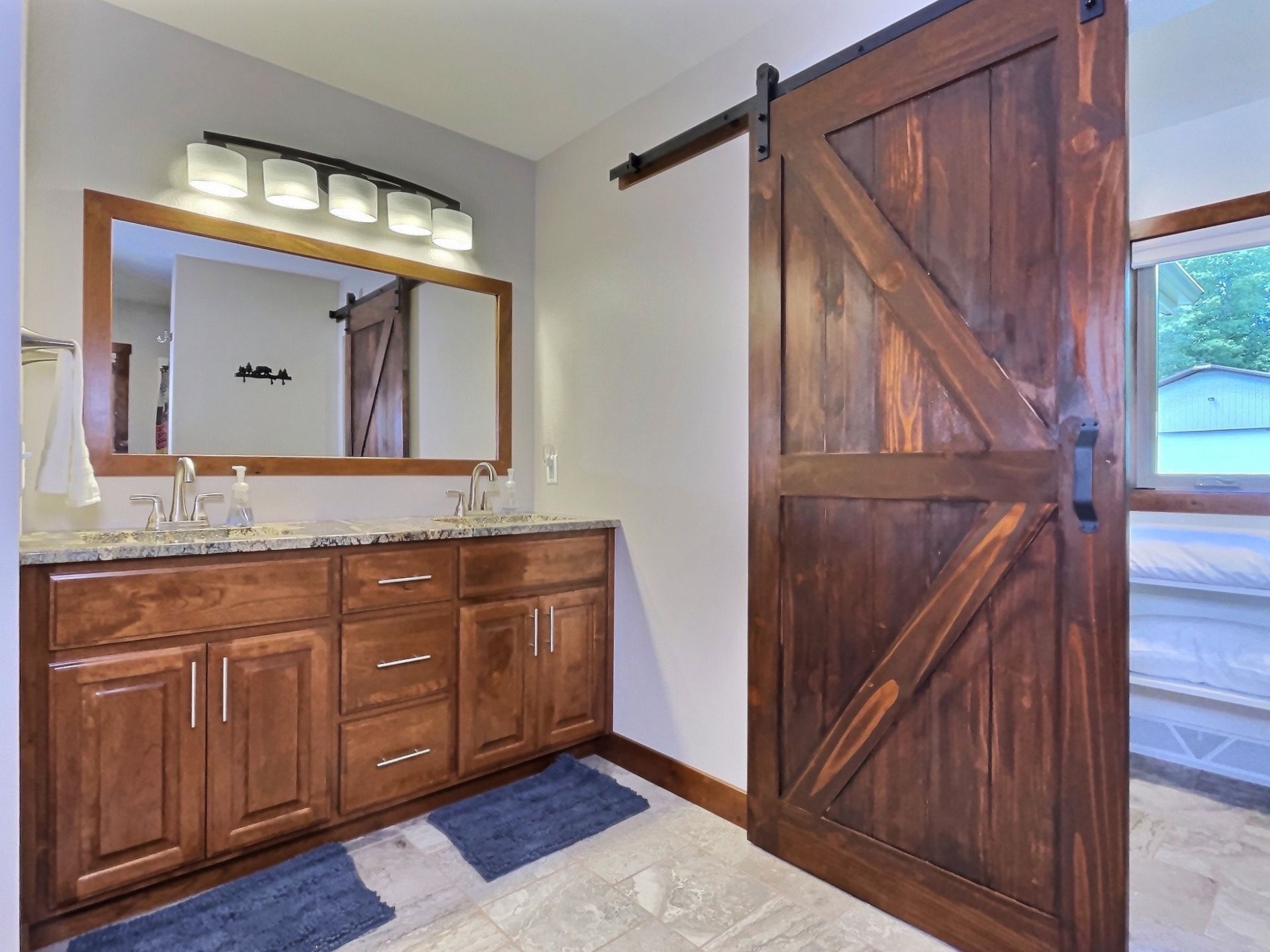Bathroom with wood barn door, vanity, and large mirror.