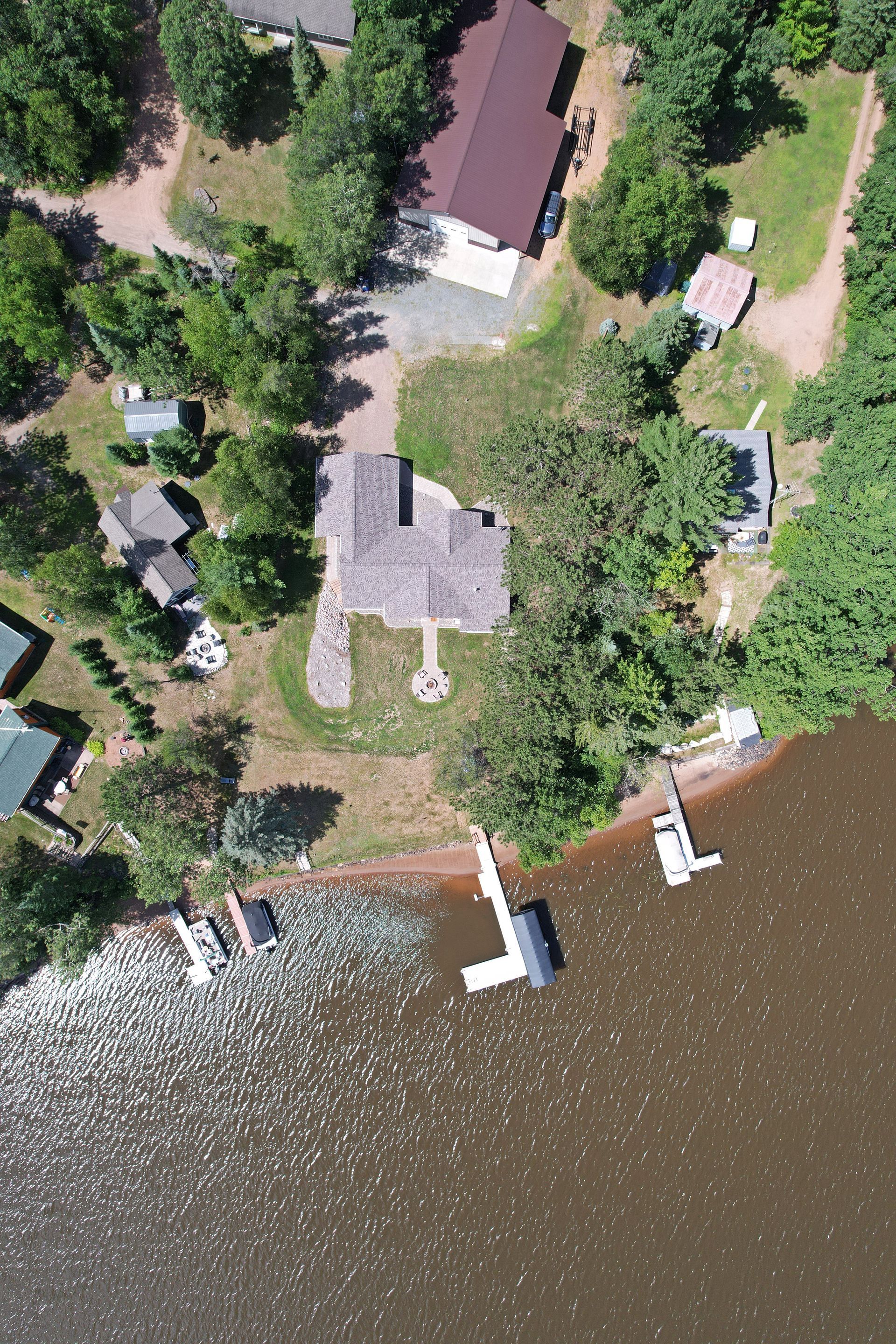 Aerial view of lakeside house with dock, surrounded by trees.