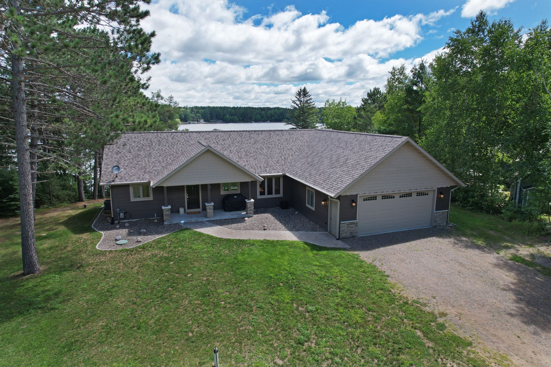 Ranch-style house with attached garage, overlooking a lake and surrounded by trees.