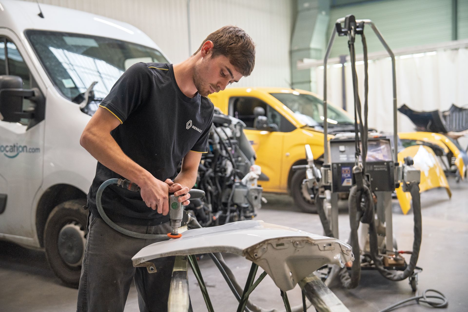 Mécanicien réalisant un débosselage de carrosserie blanche