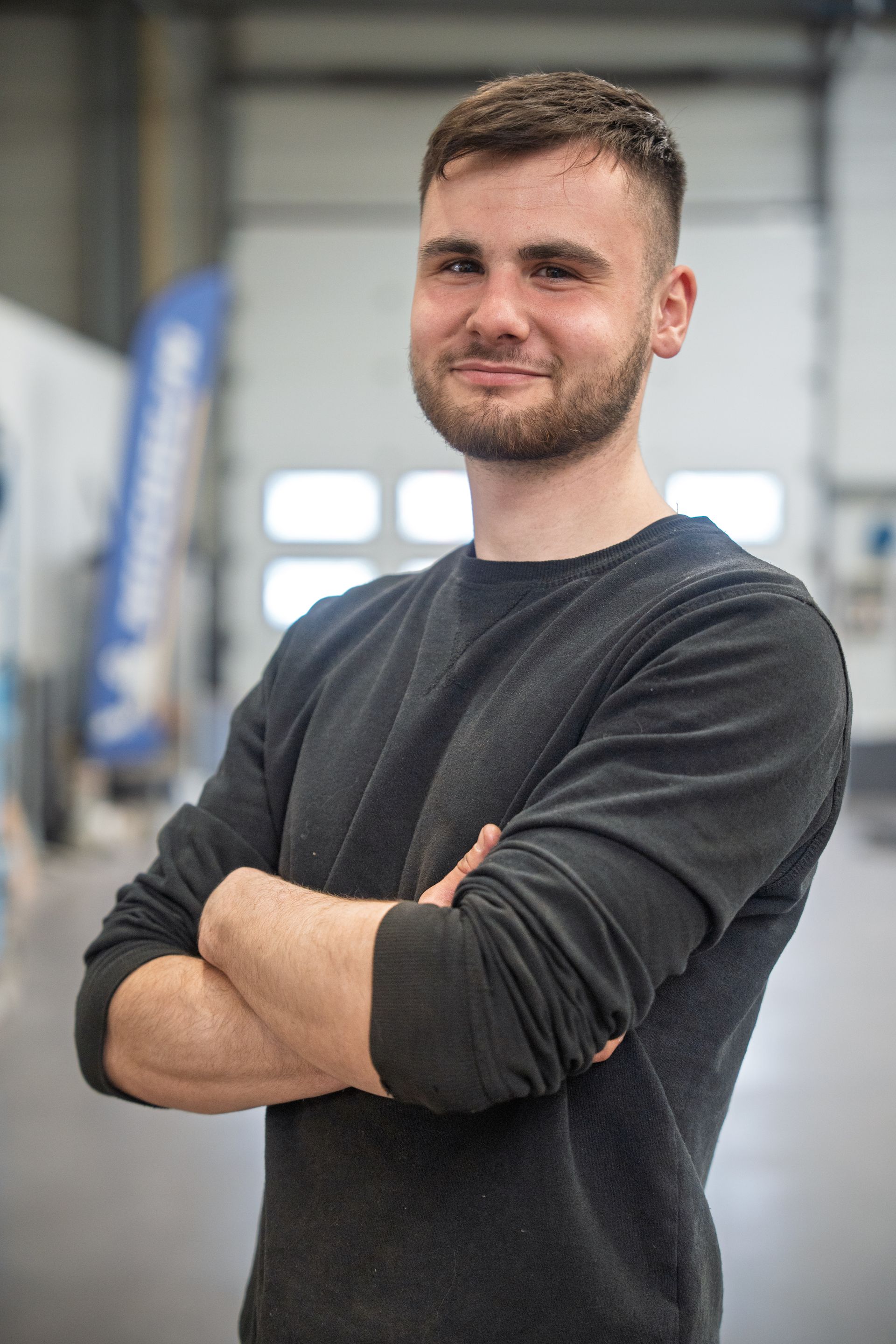 Mécanicien automobile croisant les bras avec l'espace atelier en arrière-plan