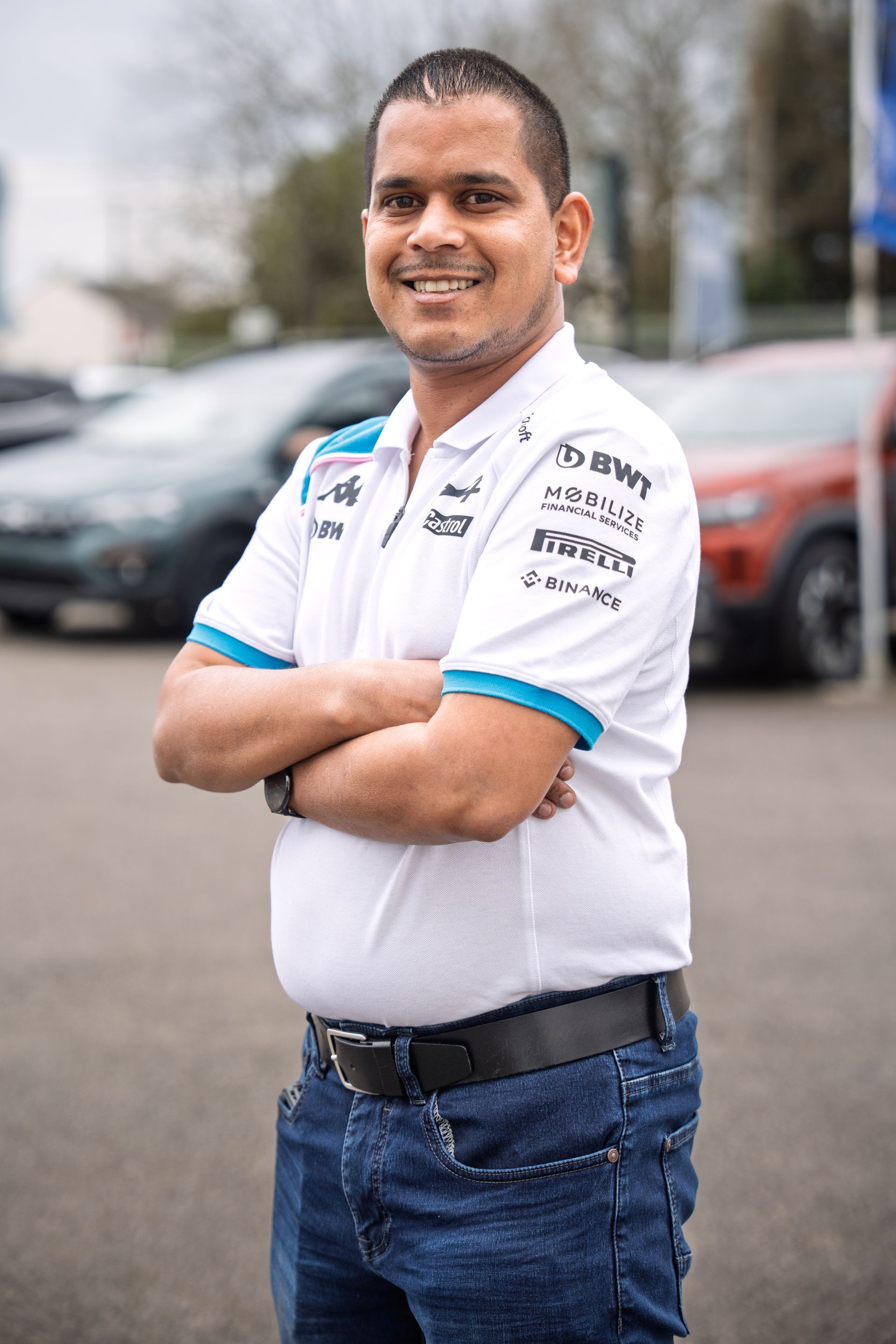 Jeune homme dans un atelier croisant les bras et portant un pull noir avec le logo Renault