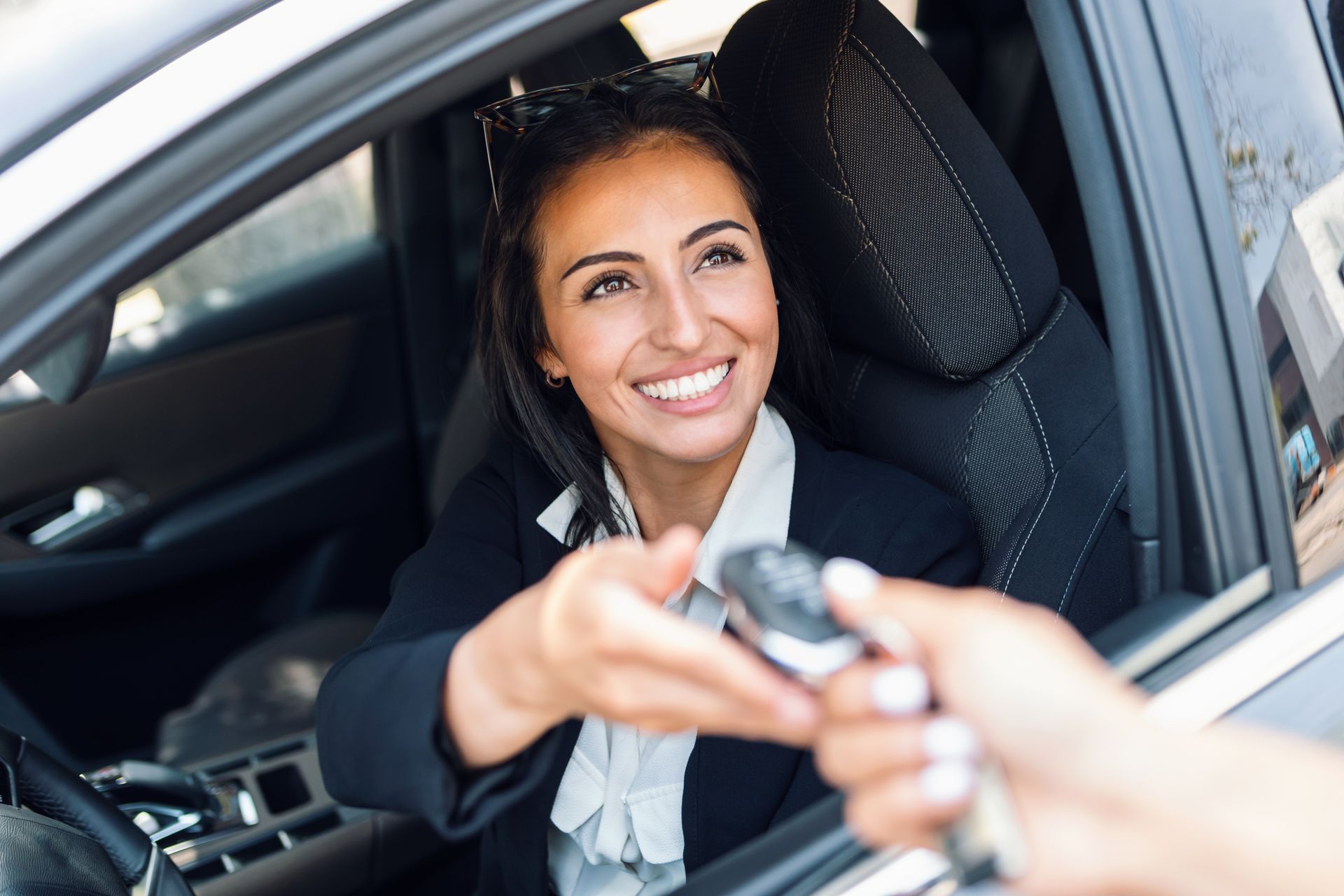 Femme souriante à bord d'un véhicule recevant une clé de voiture