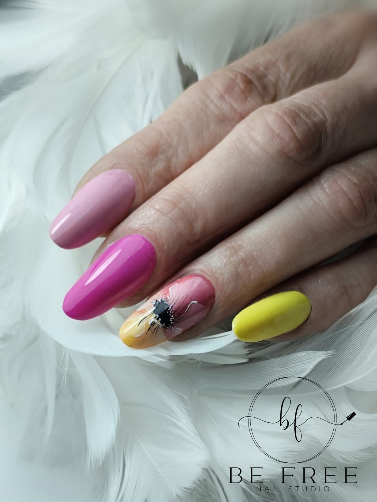 Mano con nail art rosa glitterata lucida e anelli dorati appoggiata su un tessuto bianco