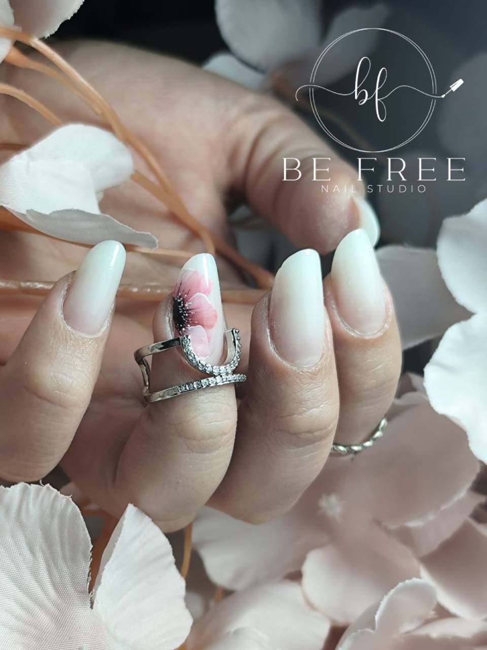 Manicure nera lucida sulla mano con dettagli a forma di piuma e una piccola filigrana con logo.