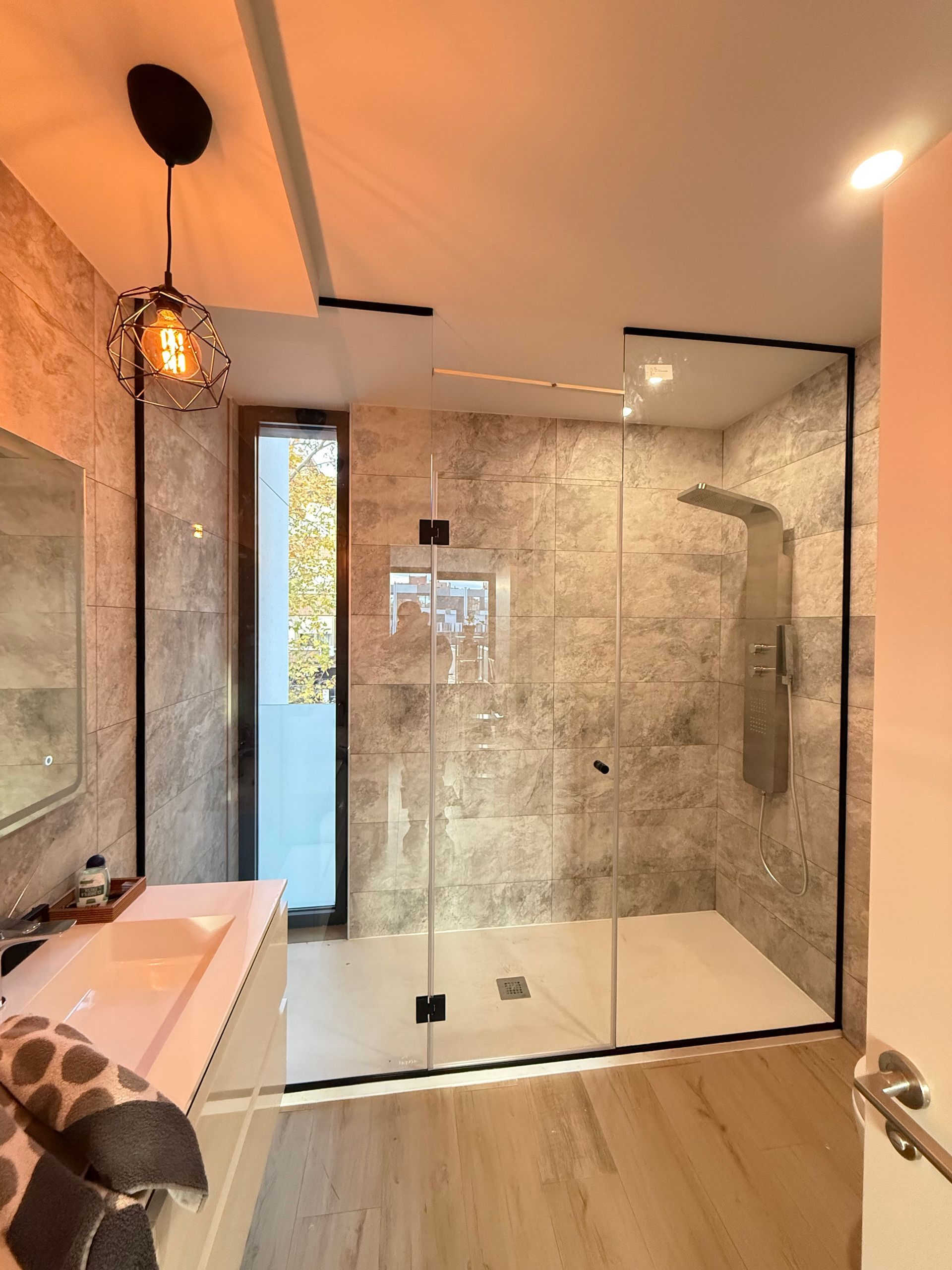 Un balcón con barandilla de cristal y pared de madera.