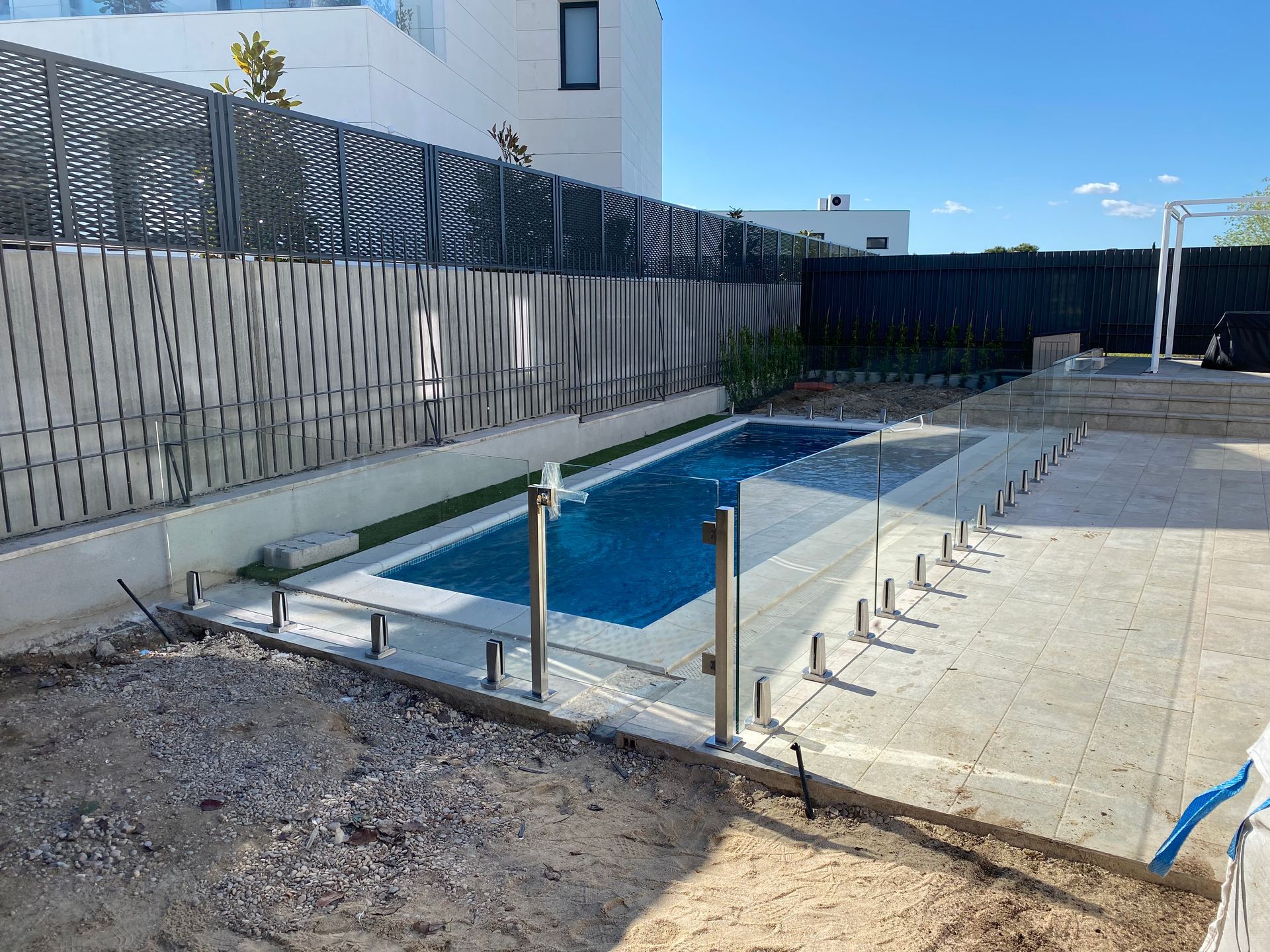 Un balcón con barandilla de cristal y plantas en macetas.