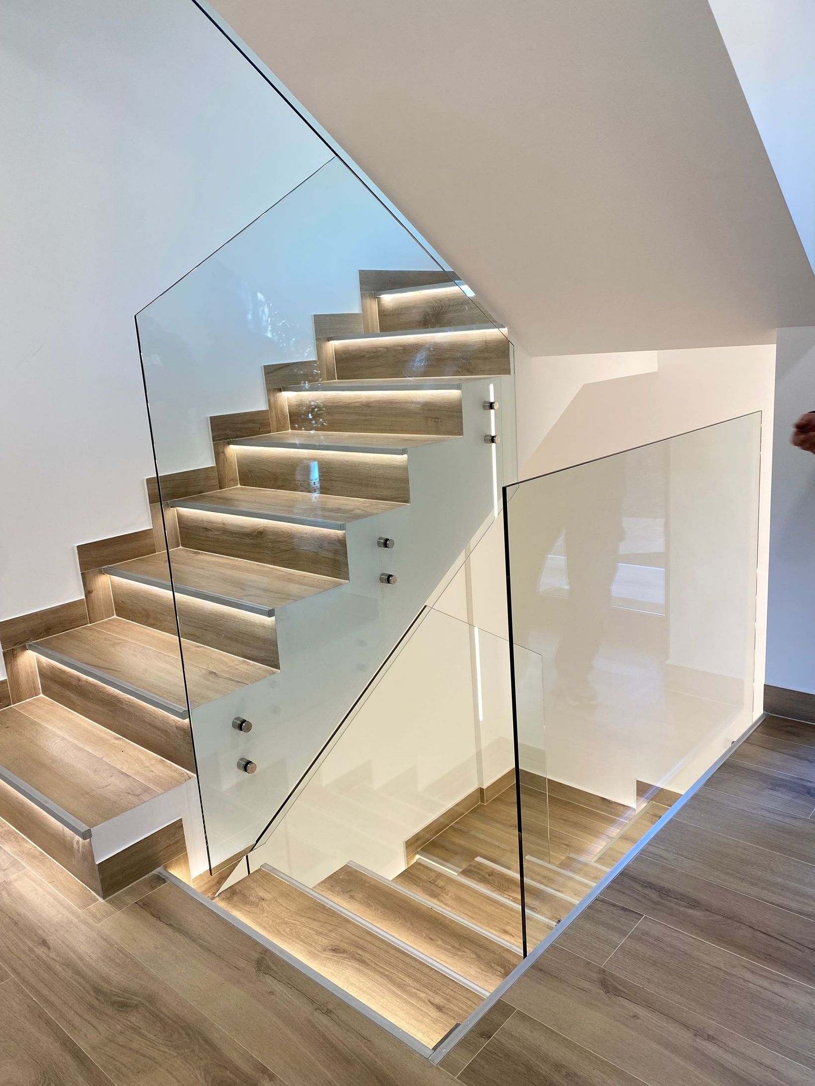 Un balcón con barandilla de cristal y pared de madera.