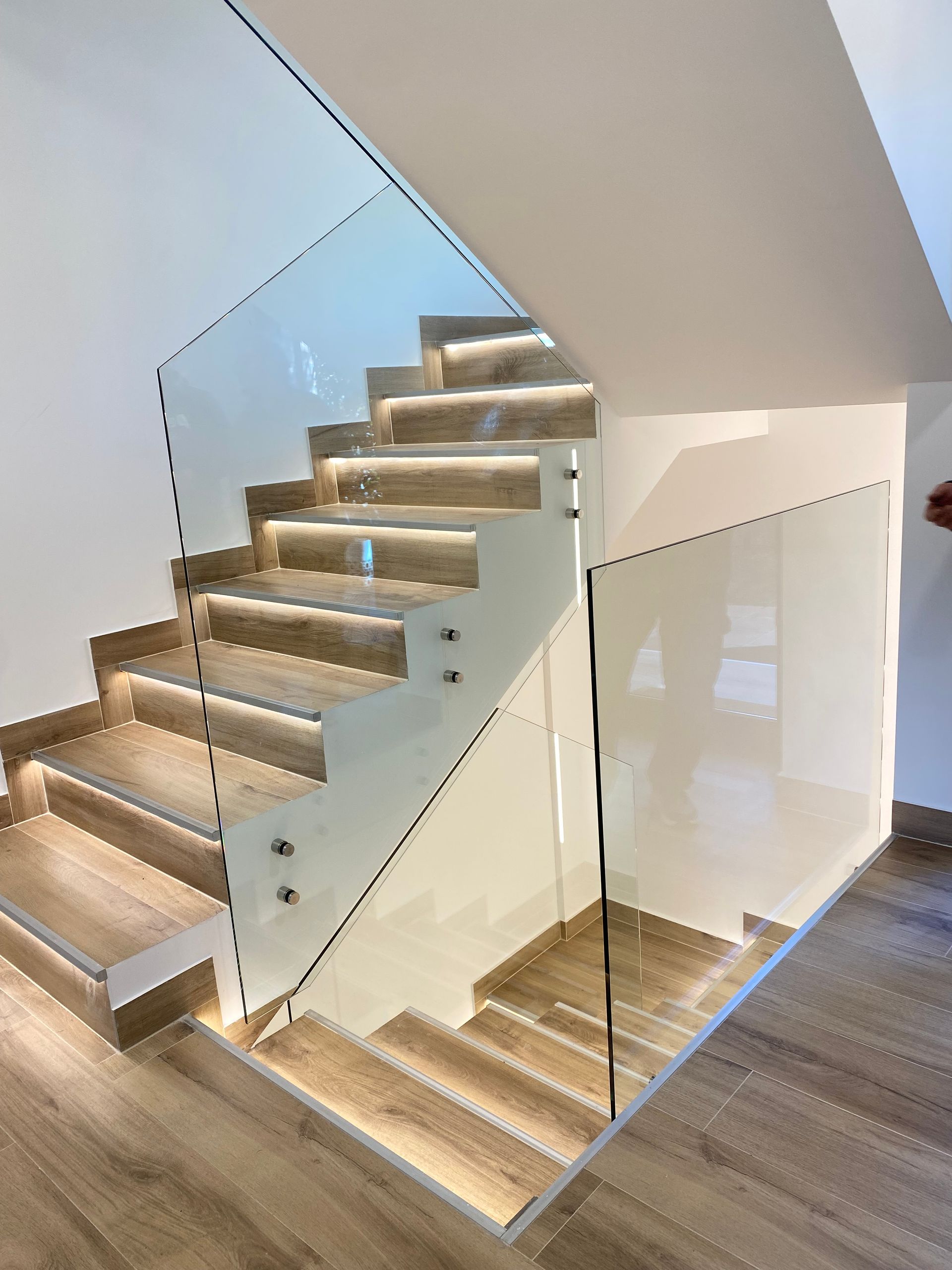 Un balcón con barandilla de cristal y pared de madera.