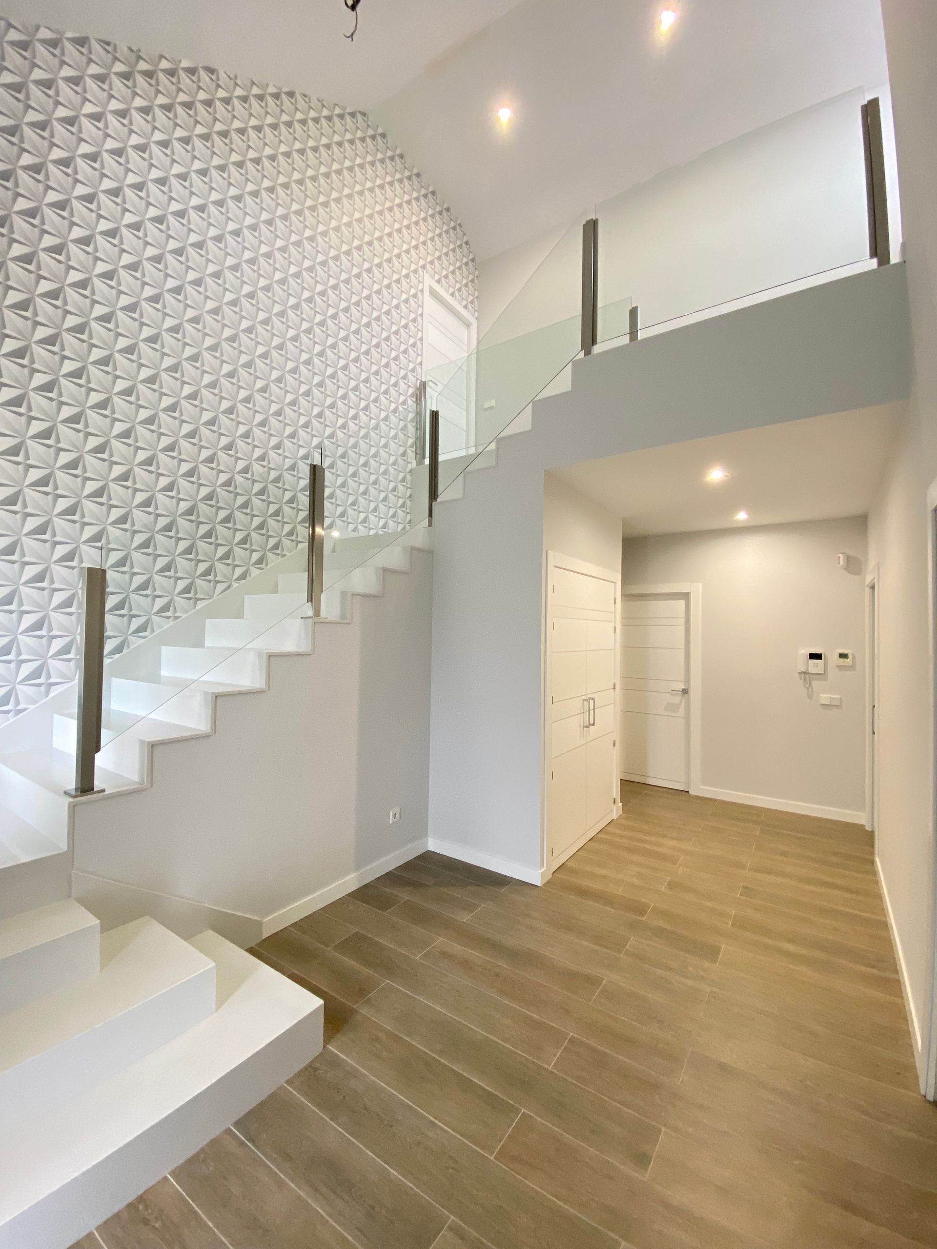 Un balcón con barandilla de cristal y plantas en macetas.