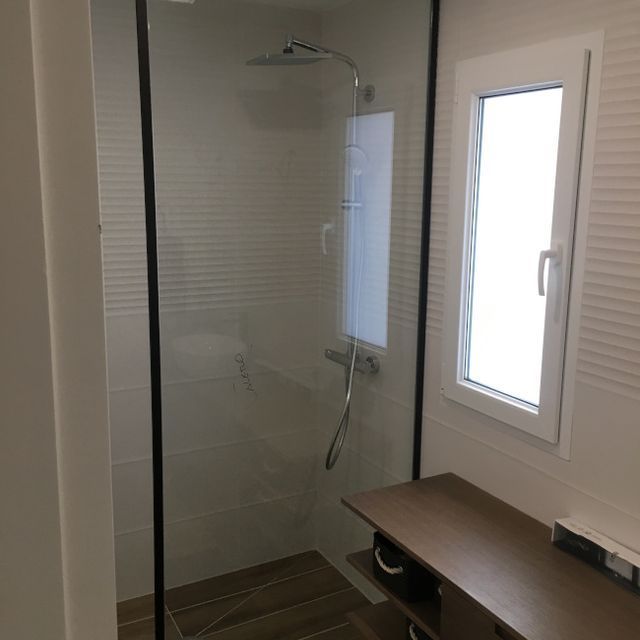 Un baño con ducha a ras de suelo y ventana.