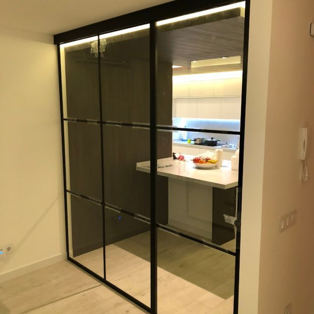 Una puerta corrediza de vidrio entre una cocina y un pasillo.