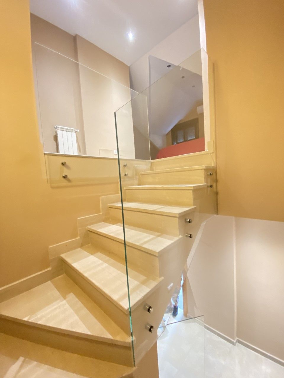 Un balcón con barandilla de cristal y plantas en macetas.