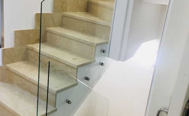 Un primer plano de una escalera con barandilla de vidrio.