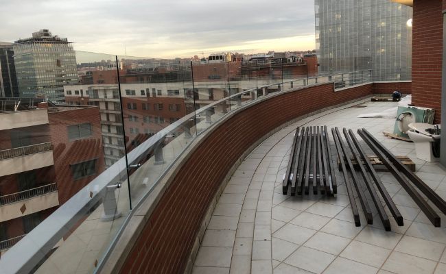 Un balcón con una pared de ladrillo y una barandilla de vidrio.
