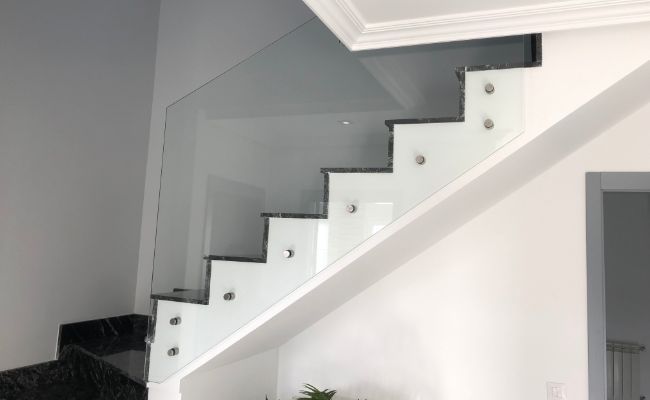 Una escalera con barandilla de cristal en una sala de estar.