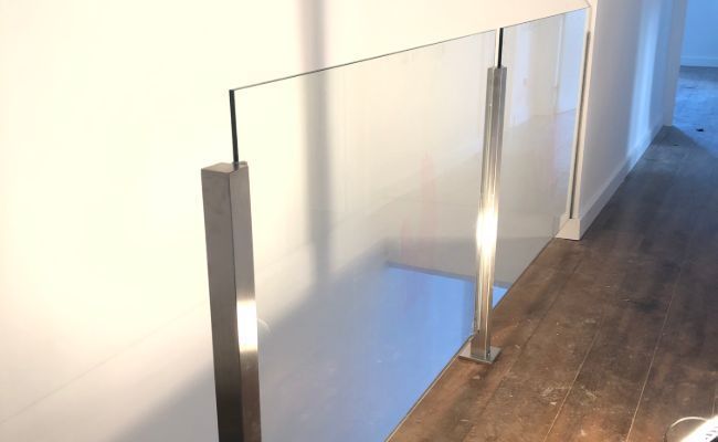 Una escalera con barandilla de cristal y suelo de madera.