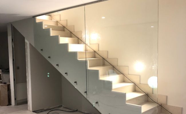 Una escalera con barandilla de cristal en una habitación.