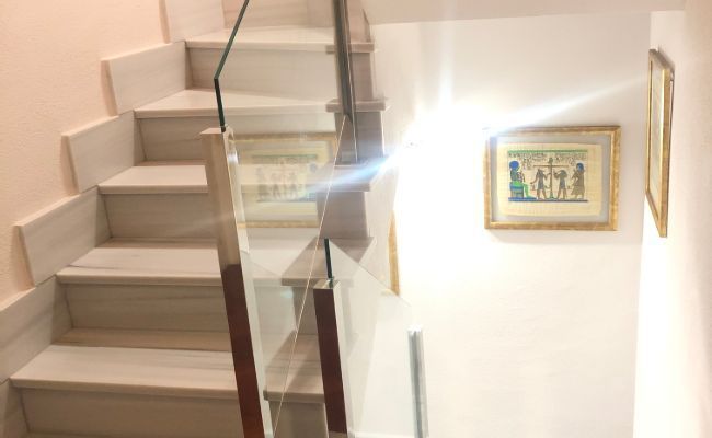 Una escalera con barandilla de cristal y un cuadro en la pared.