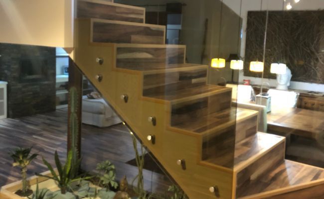 Una escalera de madera con barandilla de vidrio en una sala de estar.