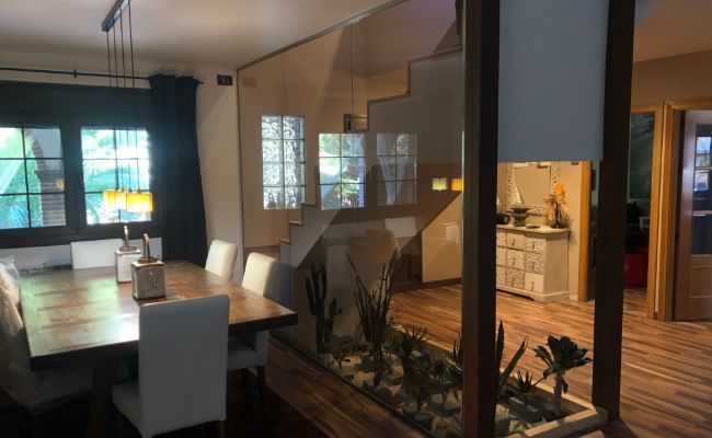 Un comedor con una mesa de madera y sillas blancas.