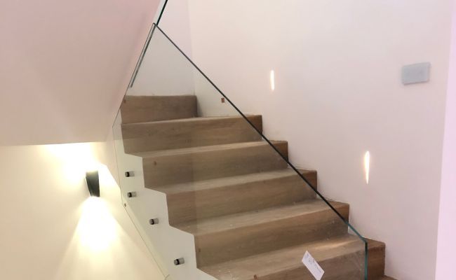 Una escalera con barandilla de cristal en una casa.