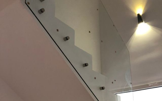 Una escalera blanca con barandilla de cristal en una habitación.