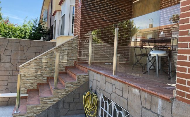 Un conjunto de escaleras que conducen a un porche con barandilla de vidrio.