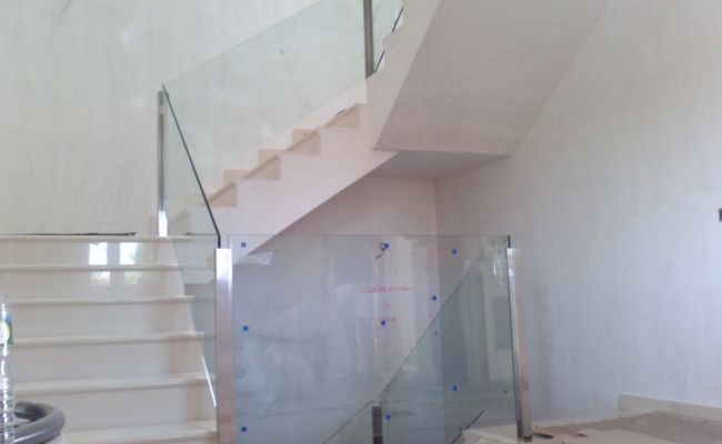 Una escalera con barandilla de cristal en una habitación.