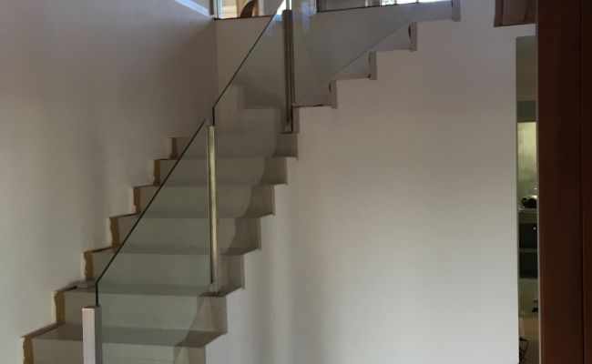 Una escalera con barandilla de cristal en una habitación.