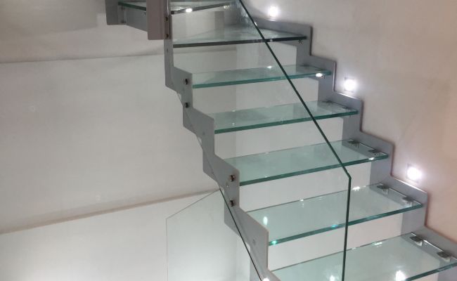 Una escalera con escalones de cristal y barandilla de cristal.